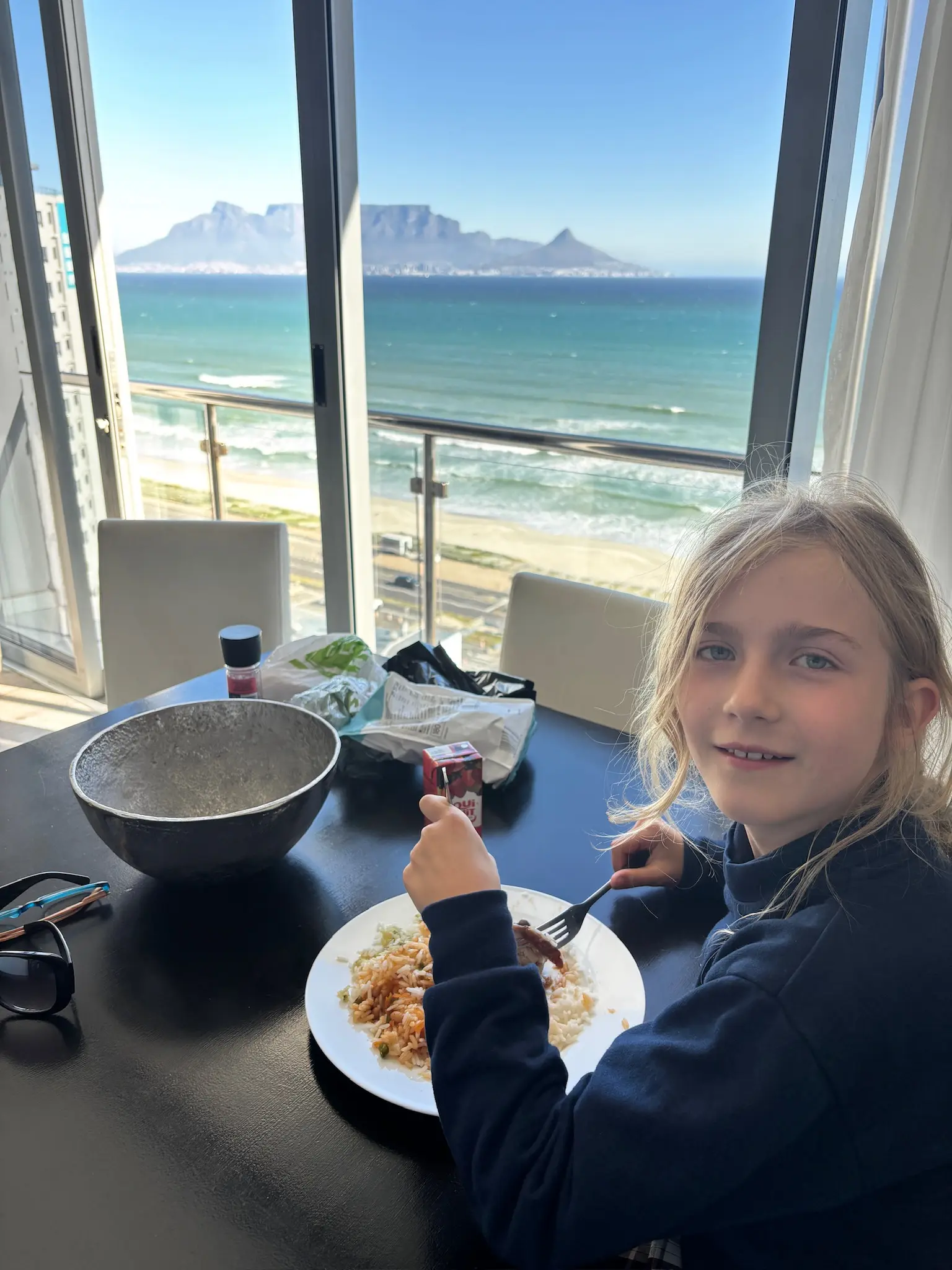 Merle isst am Tisch, im Fenster das Tafelberg-Panorama